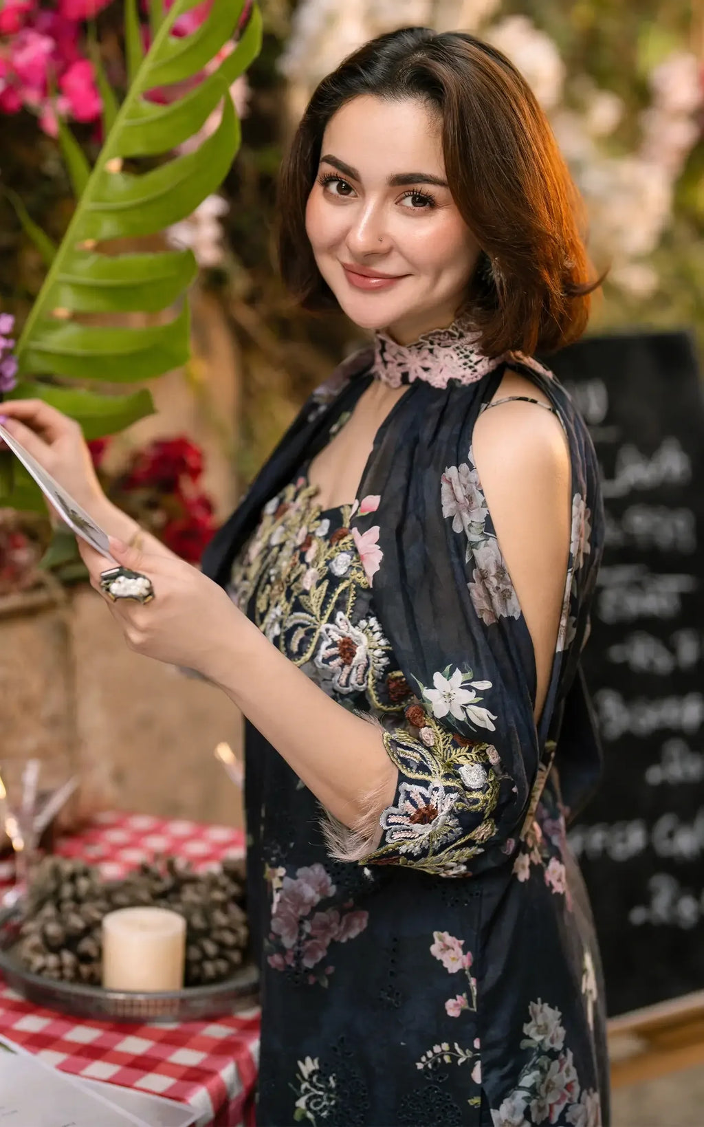 Woman in a floral dress holding a phone in a decorated indoor setting