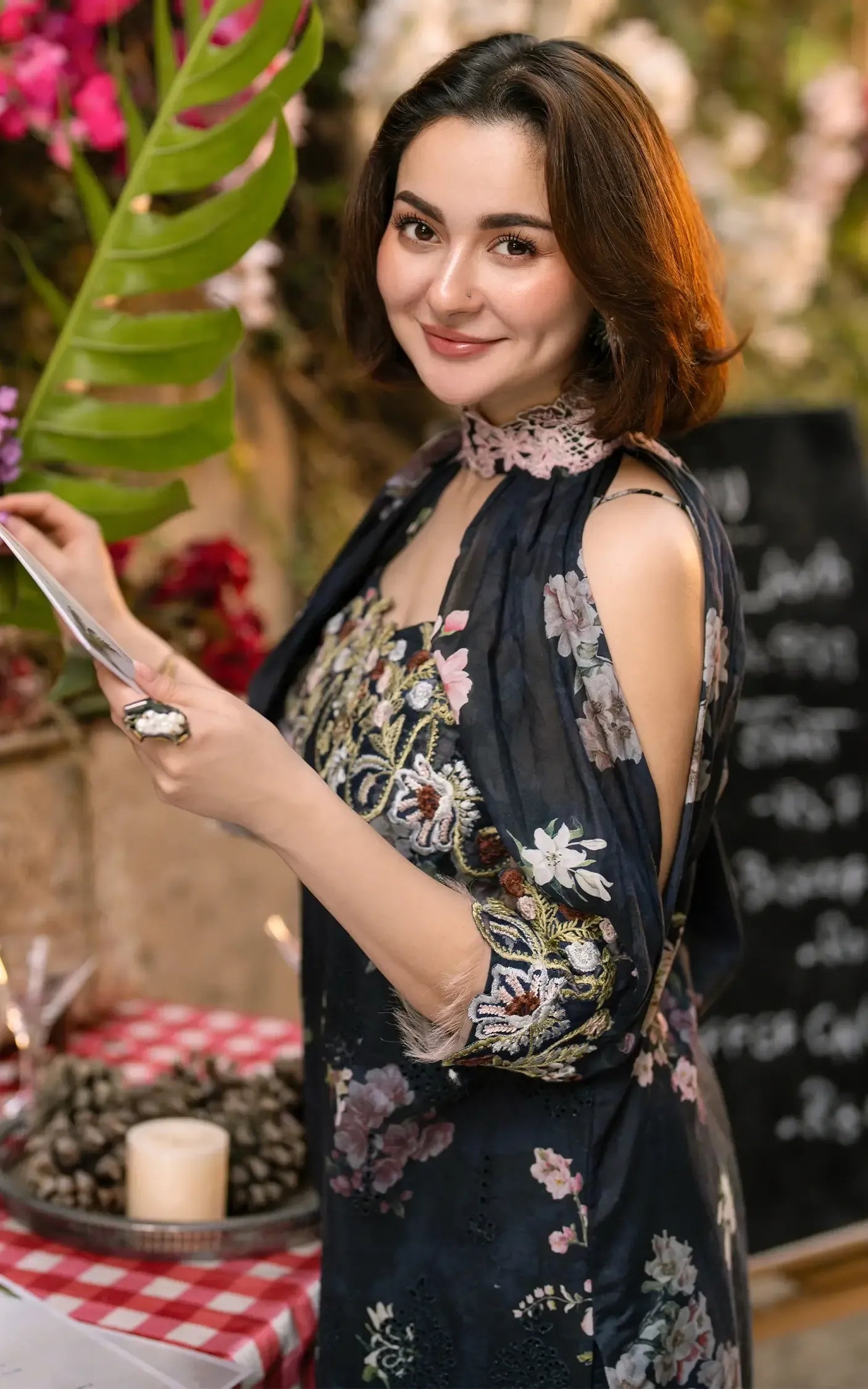 Woman in a floral dress holding a phone in a decorated indoor setting