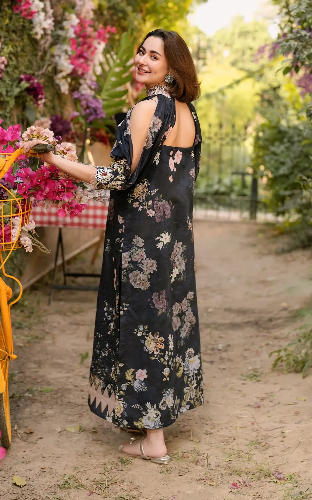 Woman in a floral dress standing in a garden with flowers and tables in the background