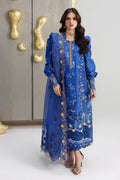 Woman wearing a blue embroidered outfit with gold details against a neutral background