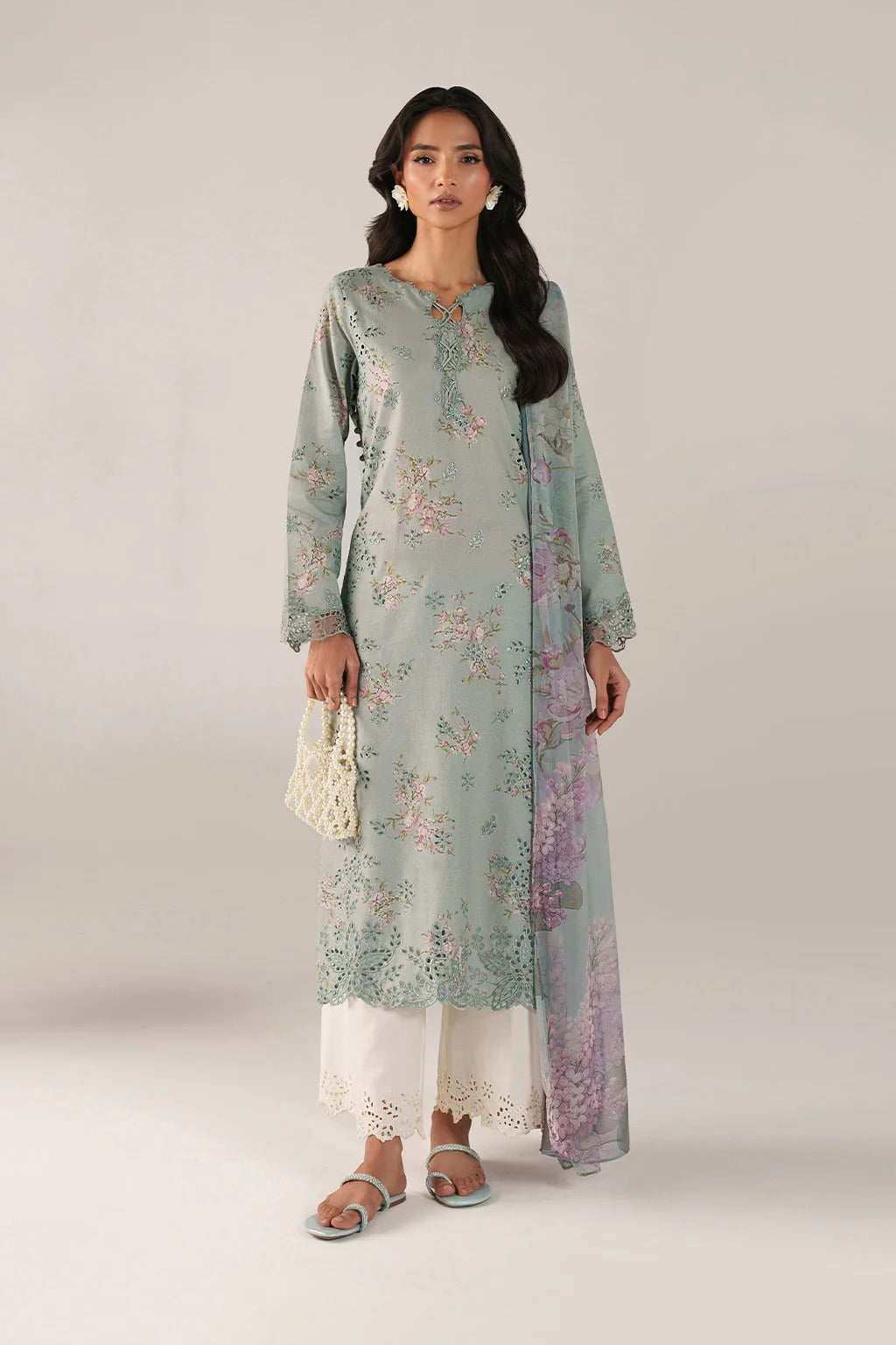 Woman wearing a light blue floral kurta with white pants on a plain background