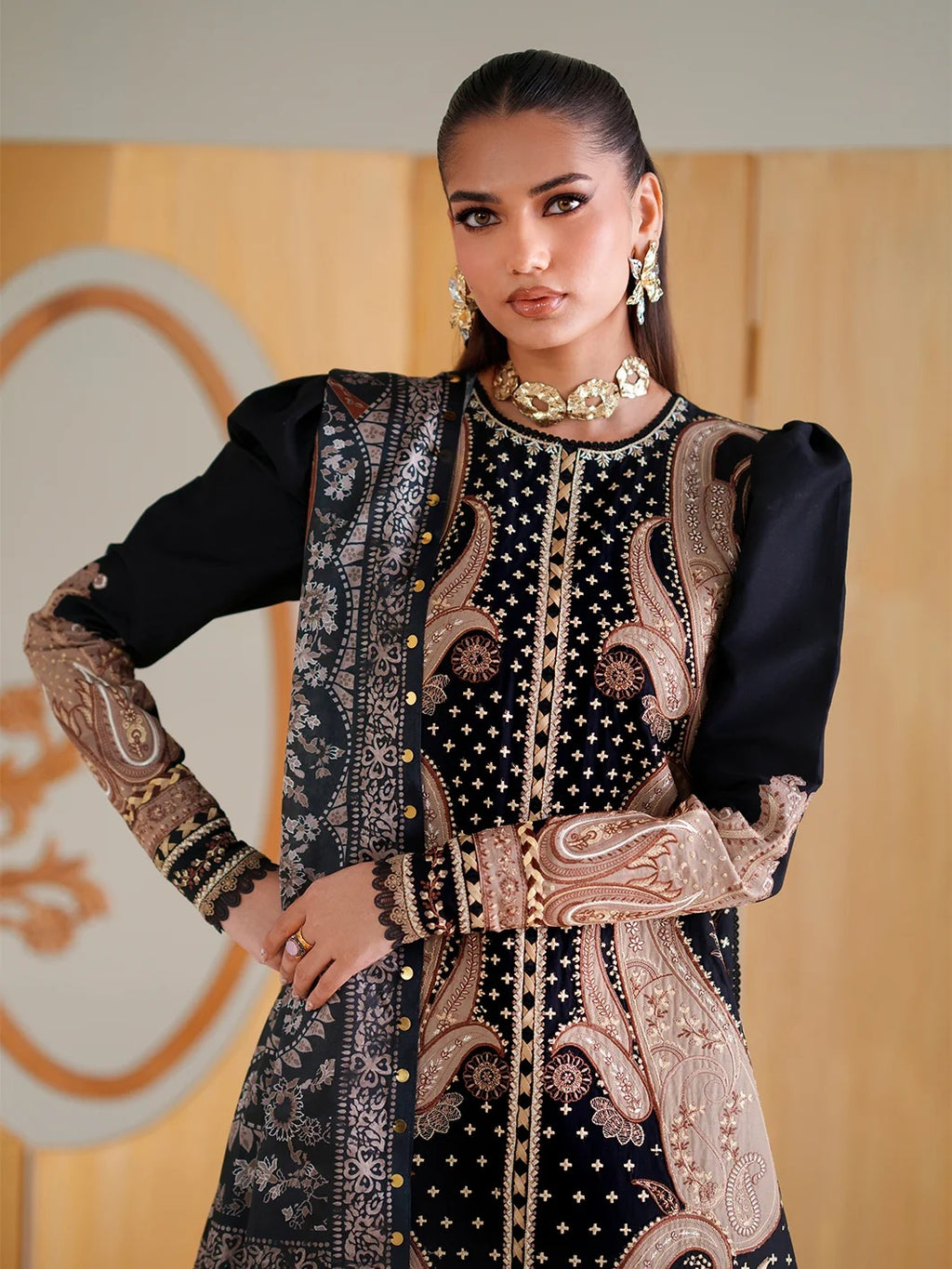 Woman wearing a black and gold embroidered traditional outfit with a blurred background