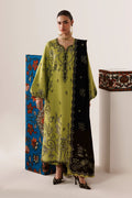 A woman models a traditional long kurta in olive green and black with intricate gold embroidery, standing in a studio setting with decorative patterned panels in the background.