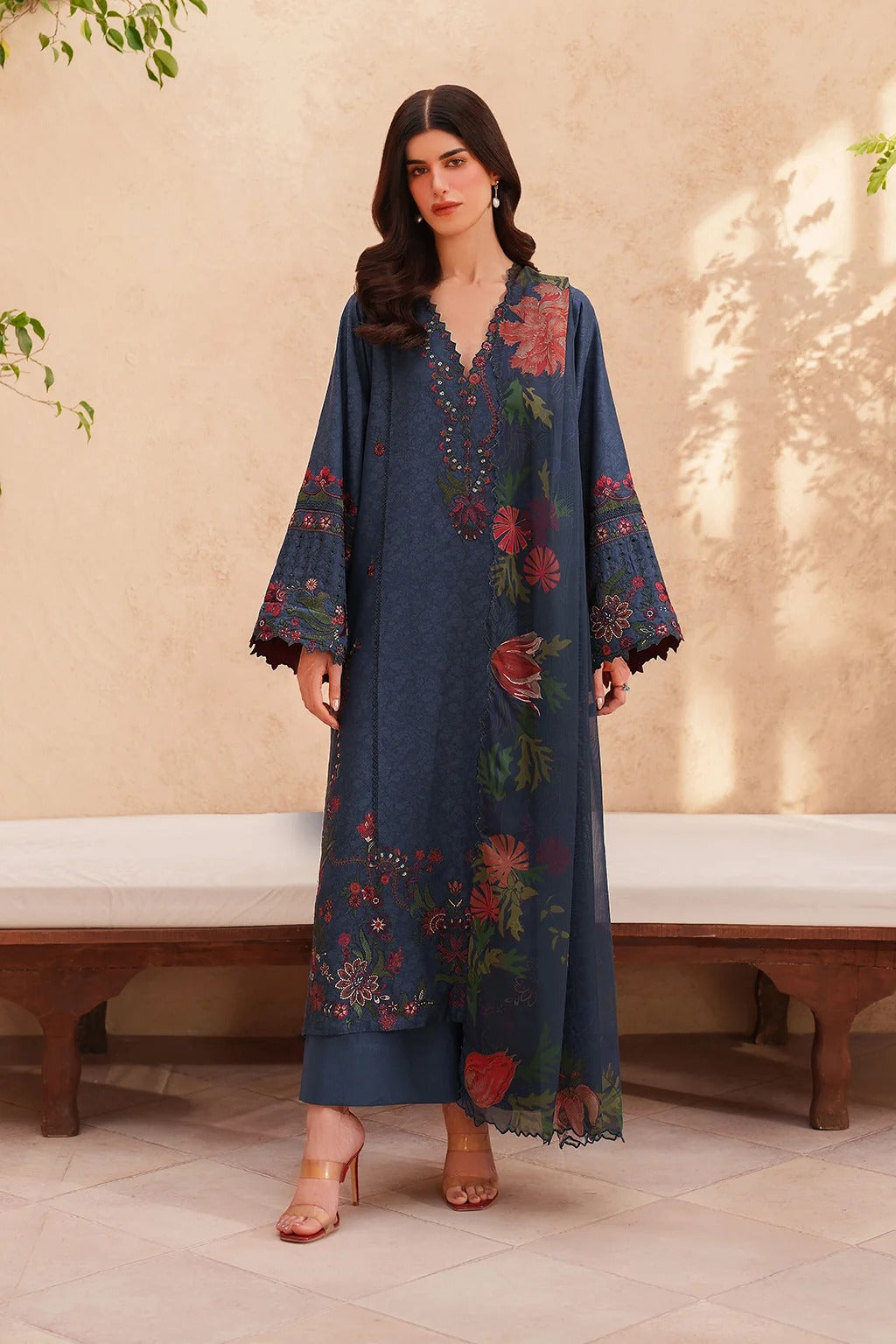 Woman wearing a blue embroidered dress in an indoor setting with a neutral background