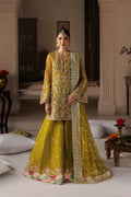 A woman models a traditional Indian ensemble featuring a mustard yellow embroidered kurta and flared pants with a matching sheer dupatta, set in an elegant indoor room.