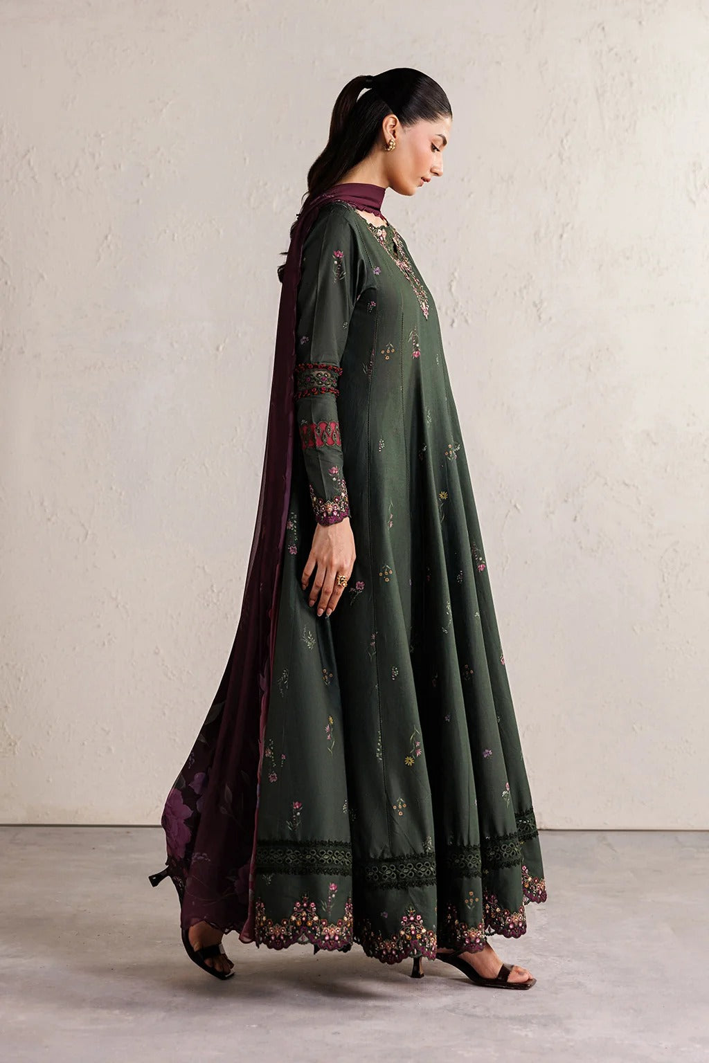 Woman wearing a green and purple traditional outfit with a plain background