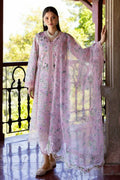 A woman models a light pink embroidered traditional outfit with a matching sheer dupatta on a sunlit balcony. The outfit features intricate floral embroidery and lace detailing.