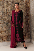 A woman models a black long kurta with deep magenta embroidery and a matching magenta dupatta, standing against a patterned brown and beige rug.