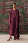 A woman models a long-sleeved, deep purple embroidered kurta with matching embellished border details, standing in front of a patterned green and red tapestry backdrop.