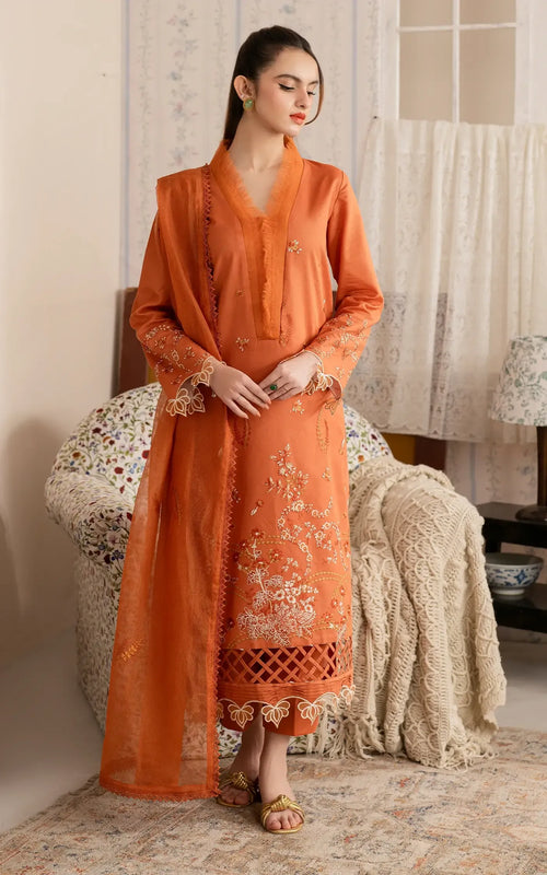 Woman in an orange traditional outfit sitting on a decorative chair.