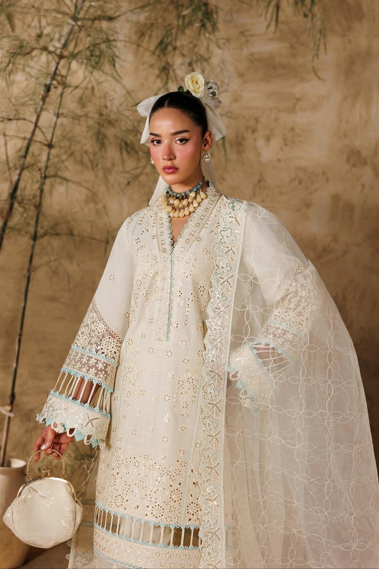 Woman in an elegant white embroidered outfit with a neutral background