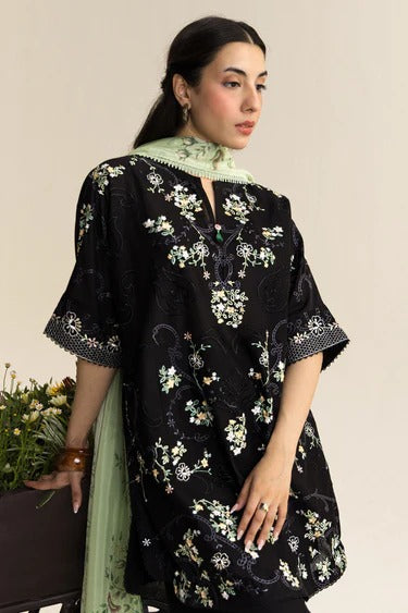Woman wearing a black embroidered dress with floral patterns on a beige background