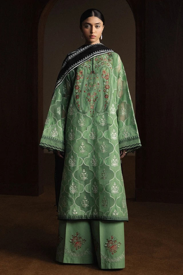 Woman wearing a green embroidered traditional outfit against a dark background