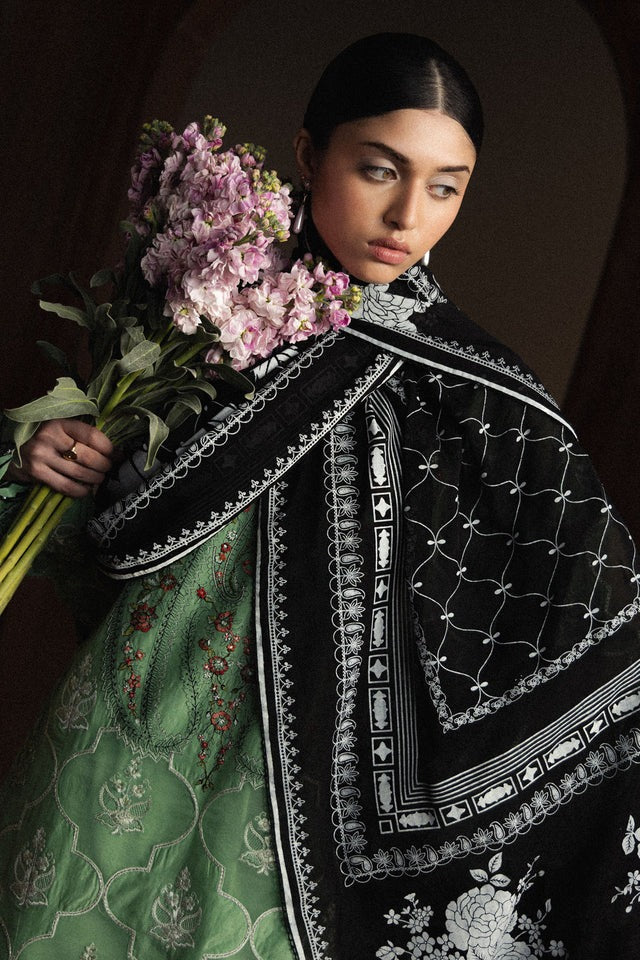 Woman holding flowers wearing a black embroidered garment with a dark background