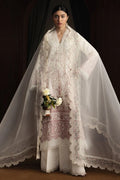 Woman wearing a white embroidered outfit with a sheer dupatta against a dark background