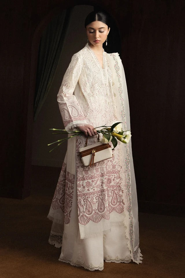 Woman in a white embroidered outfit holding flowers against a dark background