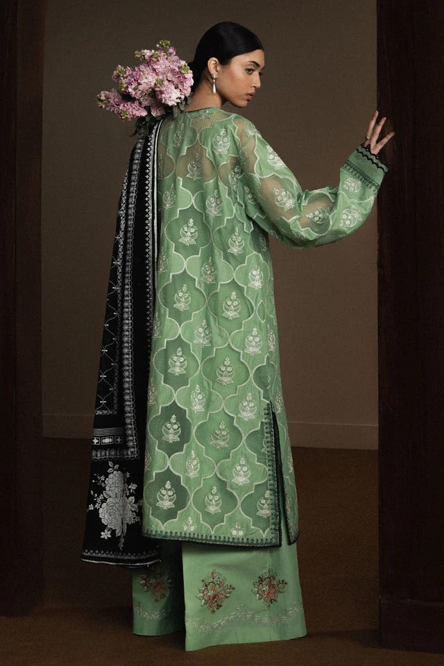 Woman wearing a green embroidered traditional outfit with a dark background