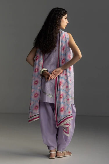 Woman wearing a light purple outfit with a floral dupatta against a gray background