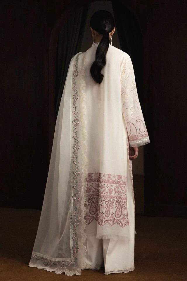 Person wearing a white embroidered outfit with a dark background