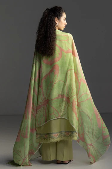 Woman wearing a green and pink floral cape over a matching outfit against a gray background