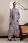 A woman models a traditional three-piece salwar kameez suit in lavender with intricate silver and pink floral embroidery, standing in a styled indoor setting.