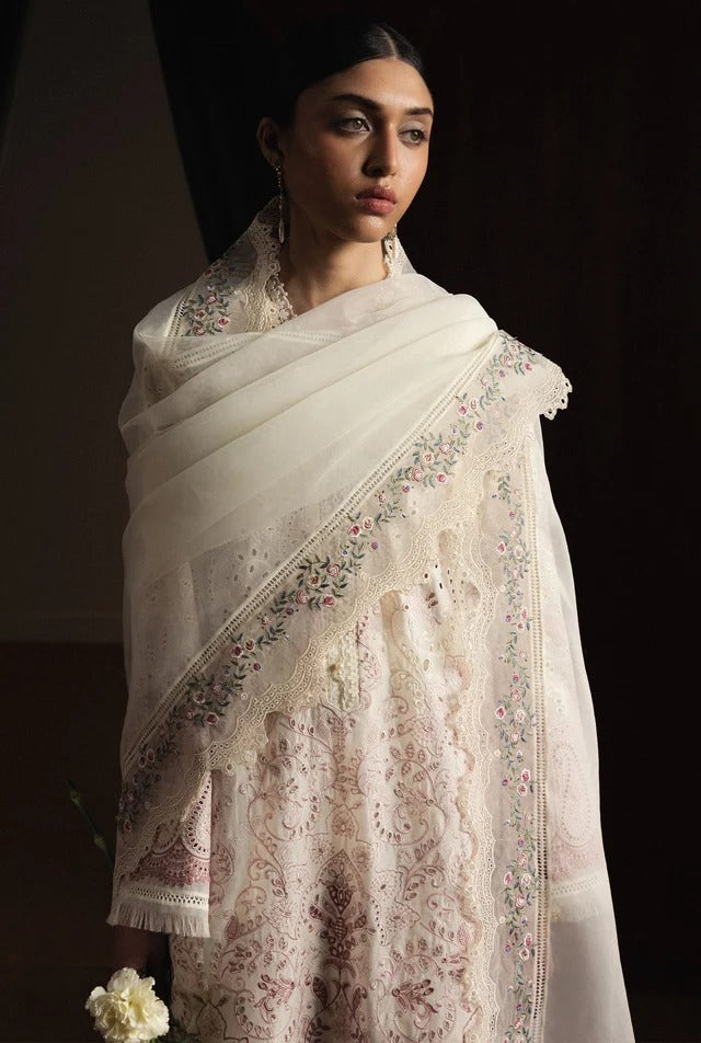 Woman wearing a white embroidered saree against a dark background