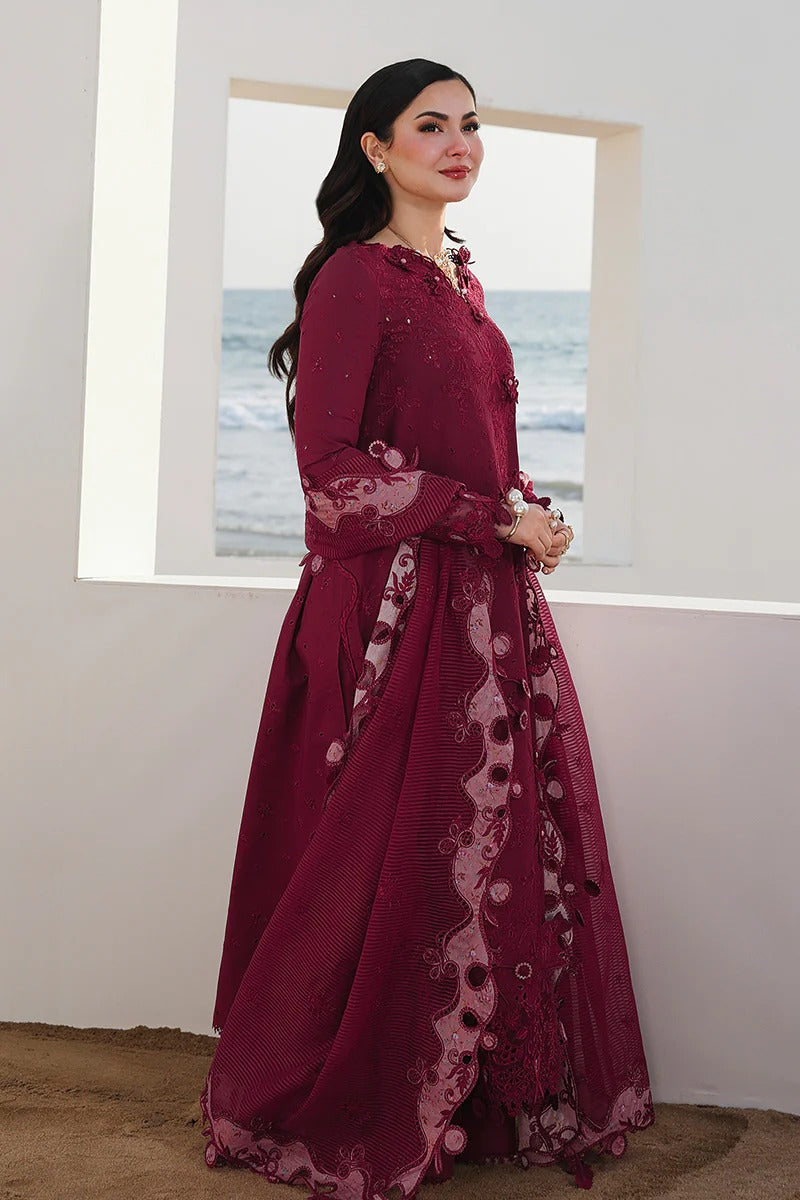 Woman wearing a burgundy embroidered dress standing in a room with a window view of water.