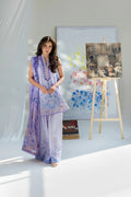 Woman in a light purple outfit standing in a room with artistic elements.