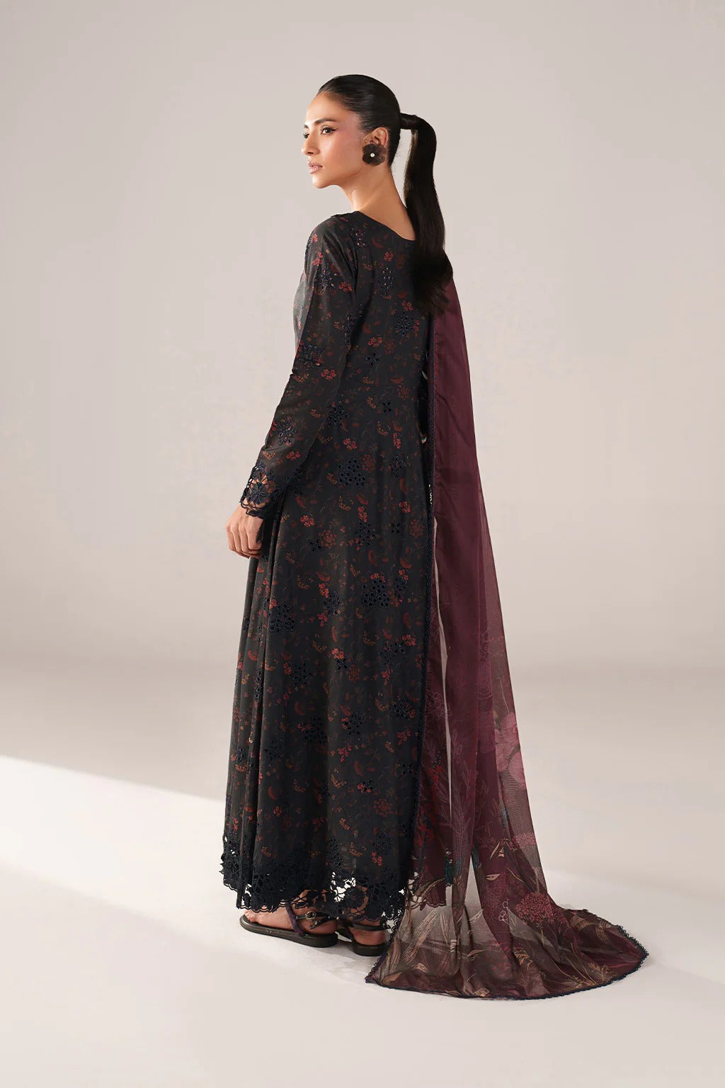Woman wearing a dark floral dress with a matching cape on a light gray background