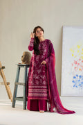 Woman in a magenta traditional outfit standing in a minimalistic room with a painting on the wall.