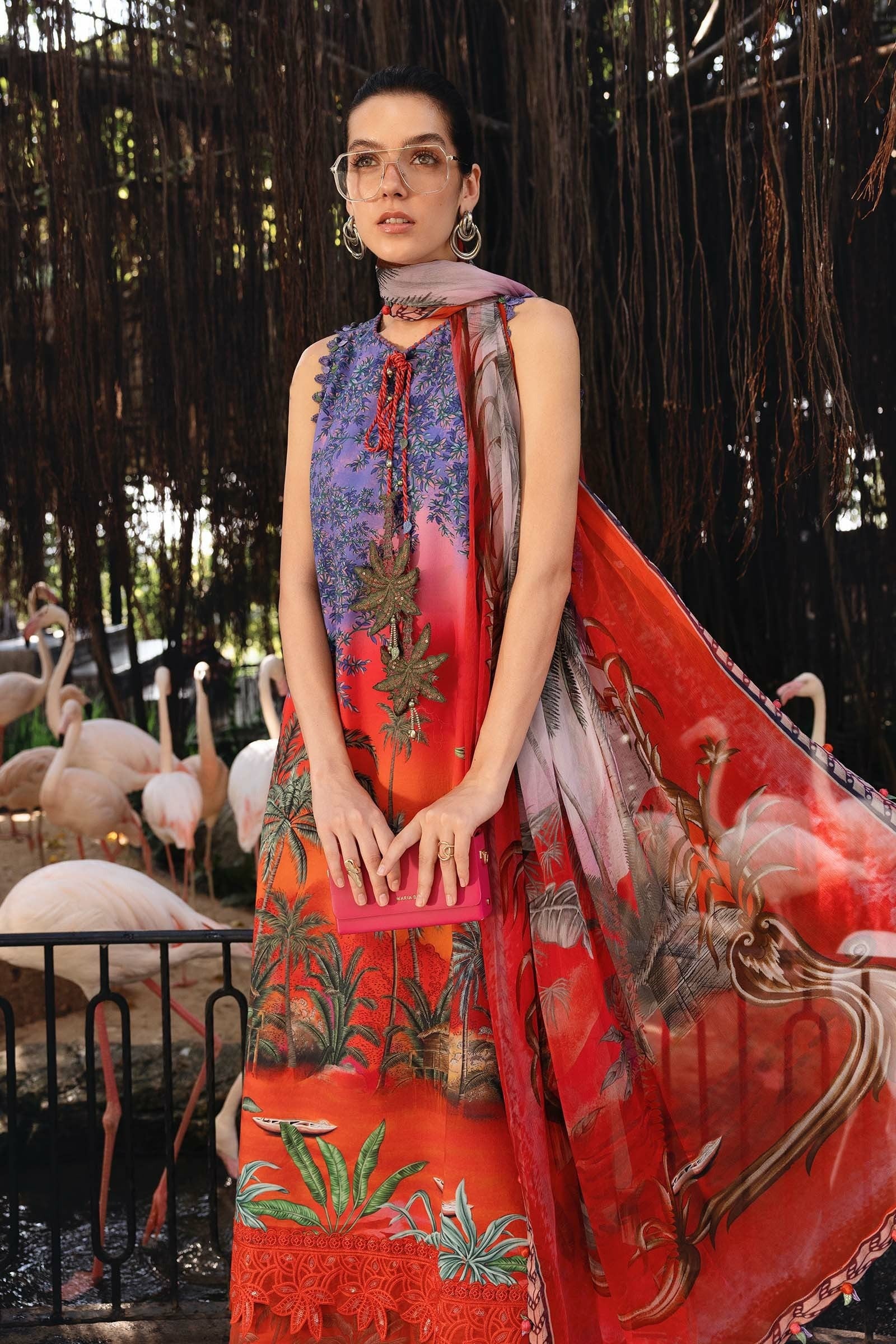 Woman wearing a colorful dress with floral patterns in an outdoor setting with flamingos.