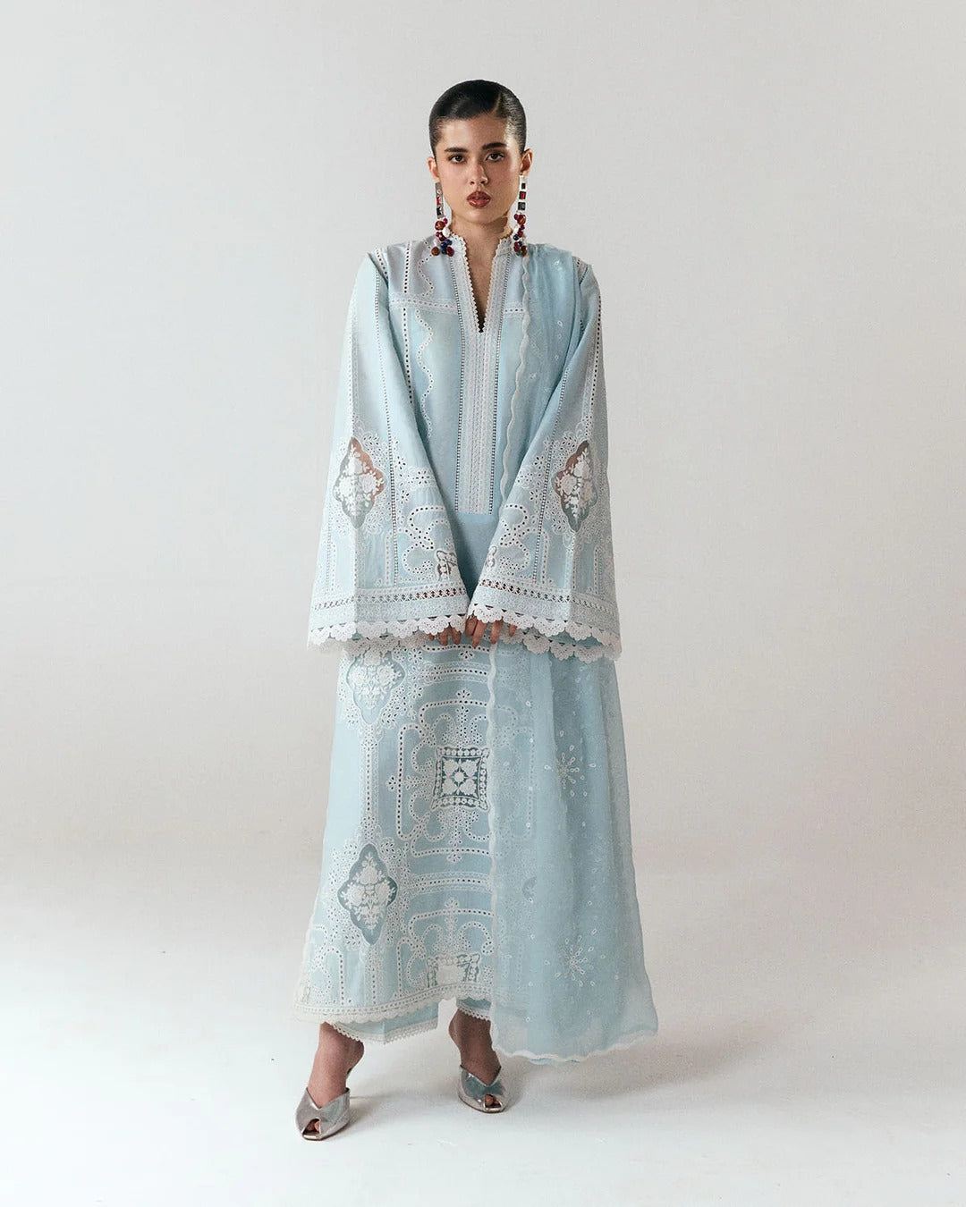 Woman wearing a light blue embroidered outfit on a white background