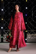 A woman models a traditional Indian outfit consisting of a magenta pink kurta and matching dupatta with intricate gold and orange embroidery, set against a dark geometric studio backdrop with lights.