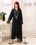 Woman wearing a black dress with intricate white patterns in a elegant room.