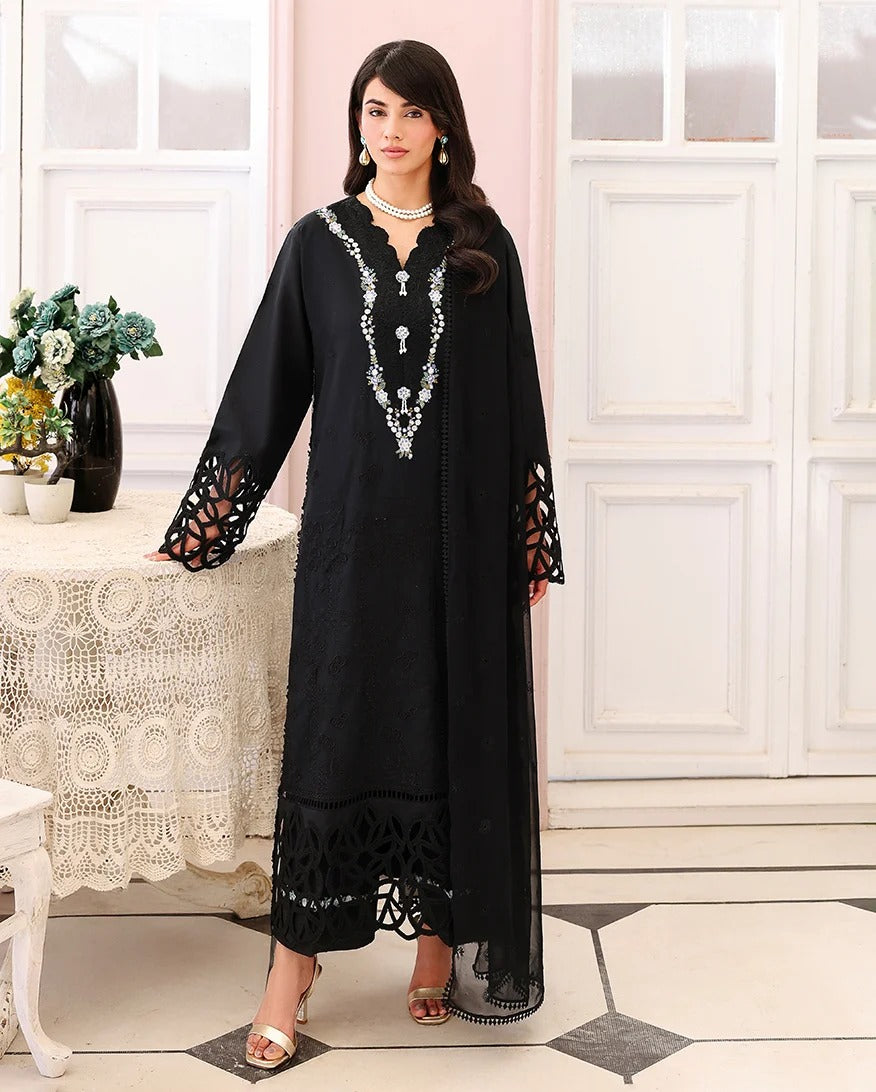 Woman wearing a black dress with intricate white patterns in a elegant room.