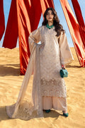 Woman in a beige embroidered outfit standing in a desert with red fabric in the background