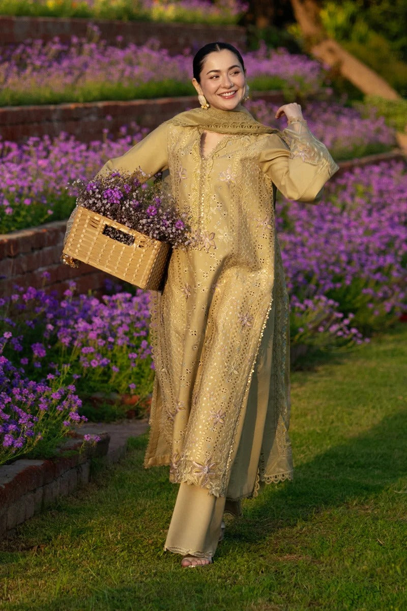Woman in a beige embroidered outfit holding flowers in a garden