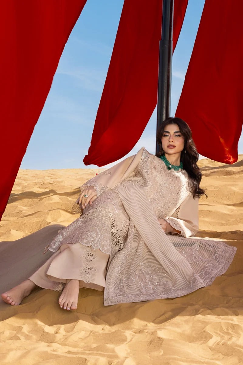 Woman in a traditional outfit sitting in the desert with red fabric in the background