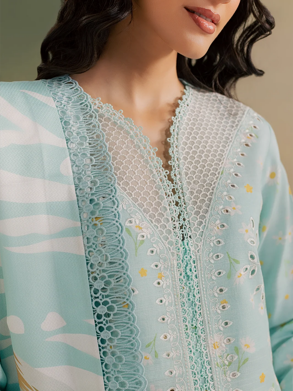 A woman shown from the back wearing a light blue embroidered kurta with a matching floral printed dupatta and white pants, standing against a soft gradient studio background.