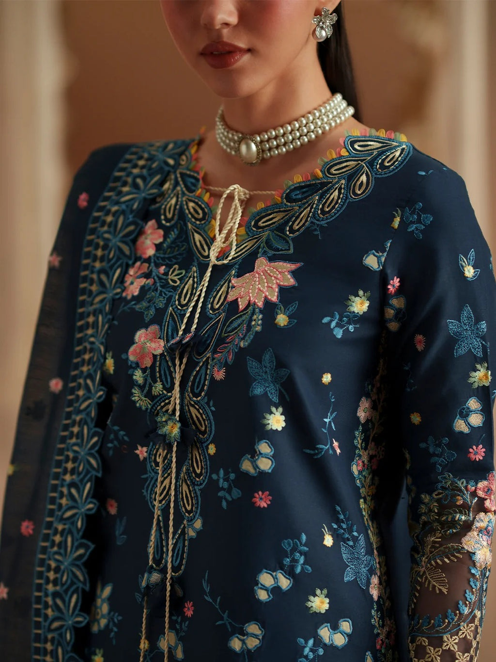 Navy blue embroidered outfit with floral patterns and a pearl necklace.
