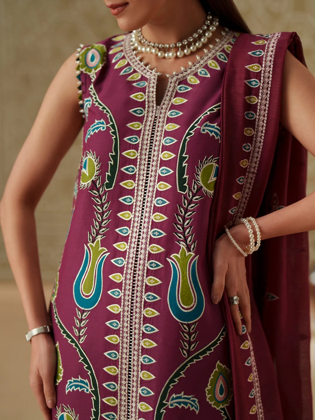 Person wearing a vibrant purple traditional outfit with intricate patterns and jewelry.