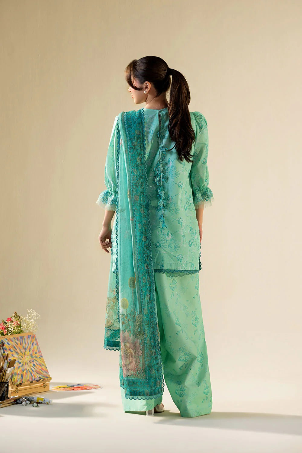 Woman wearing a light green traditional outfit with a matching dupatta on a beige background