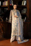 Woman in a traditional outfit with floral patterns standing in front of a bookshelf.