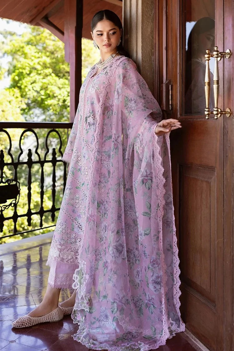 A woman models a light pink floral printed sheer maxi dress with wide sleeves and lace trim, standing on a wooden porch with a green garden background.