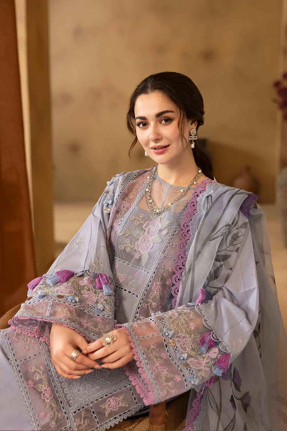 Woman wearing a traditional embroidered outfit with a neutral background