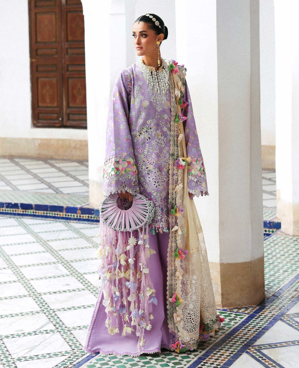 Woman in a traditional outfit with floral patterns in a decorative interior setting