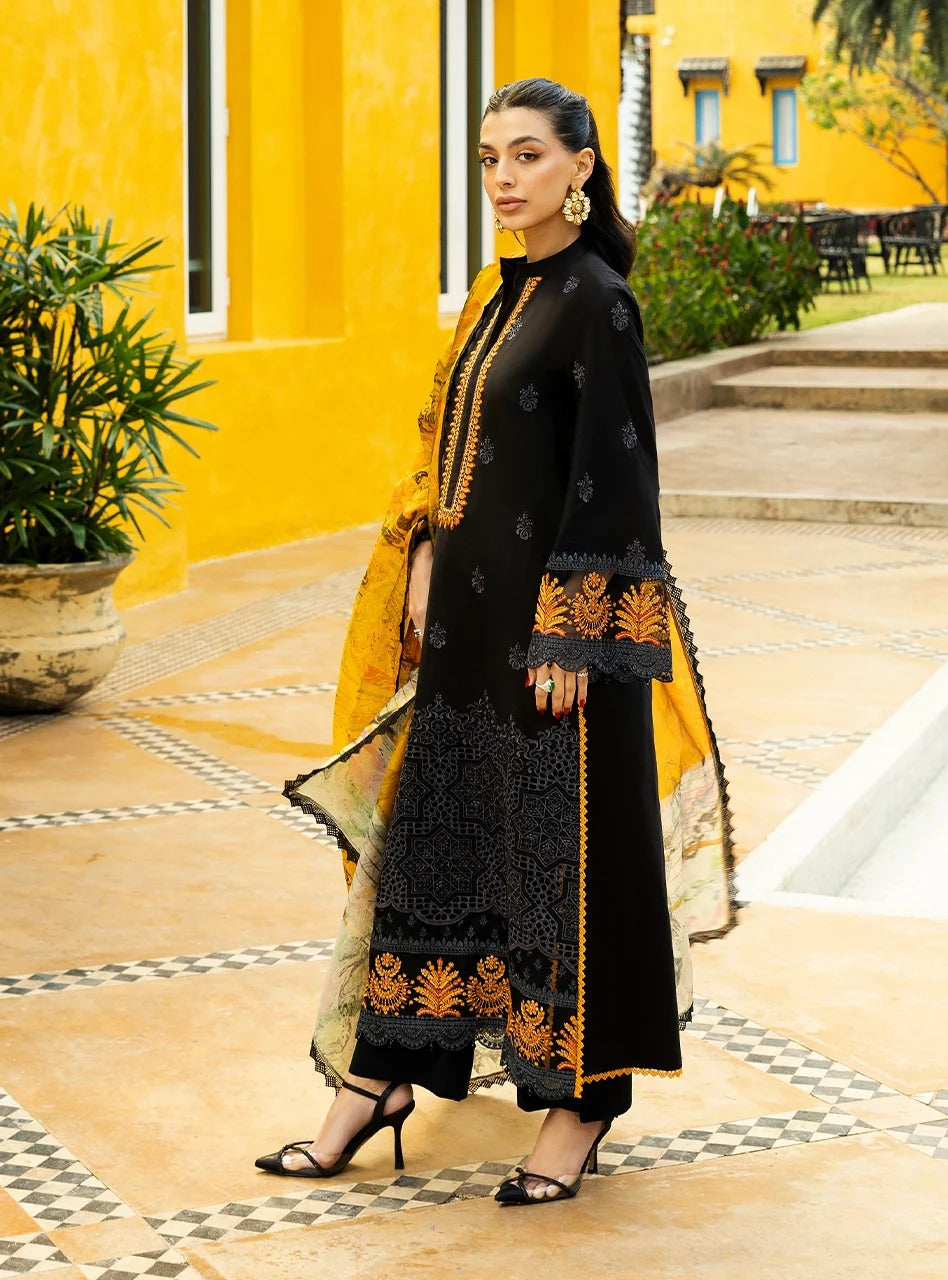 Woman in black and yellow traditional outfit standing on a patterned floor with a yellow wall and plants in the background.