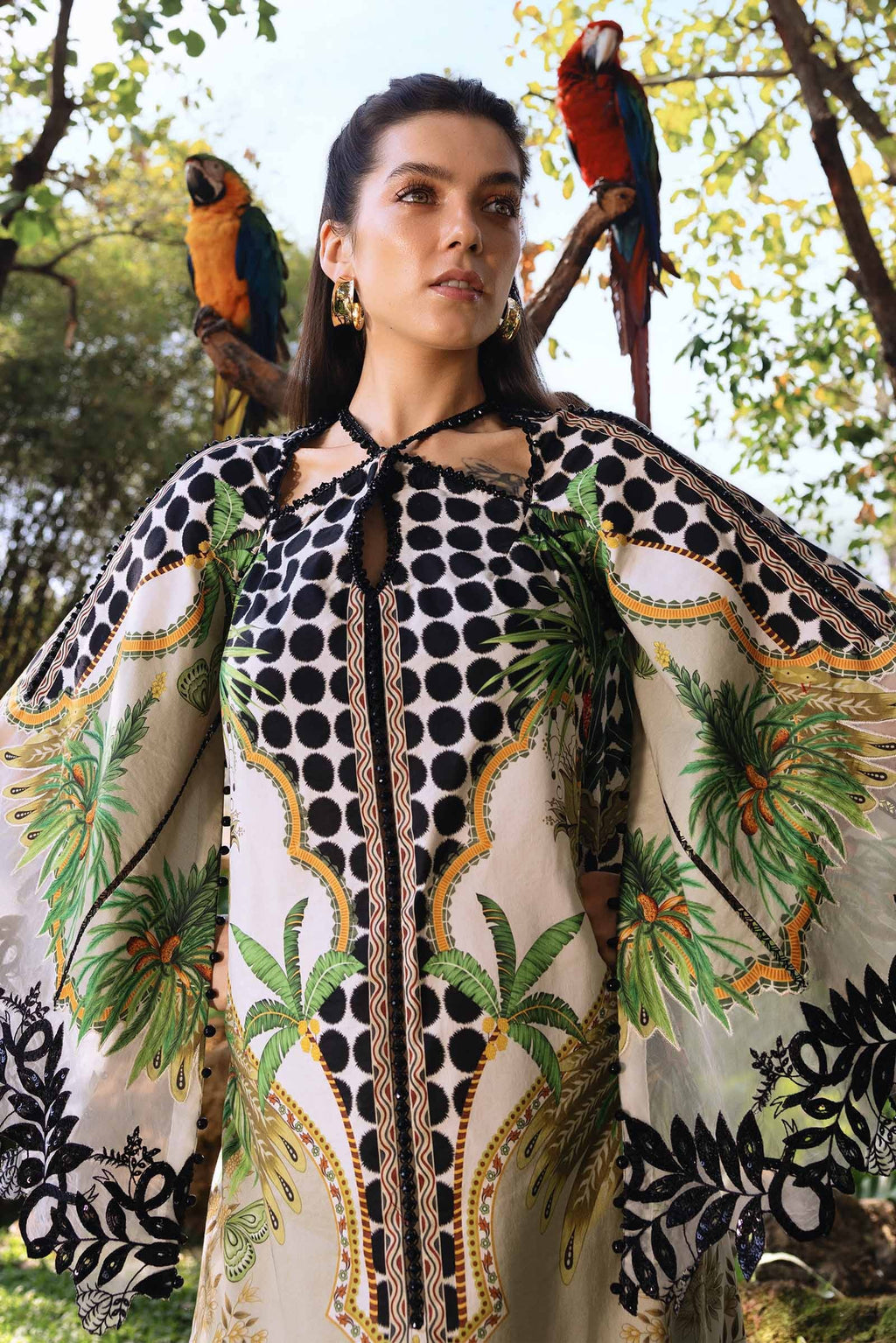Woman wearing a patterned outfit with parrots on trees in the background