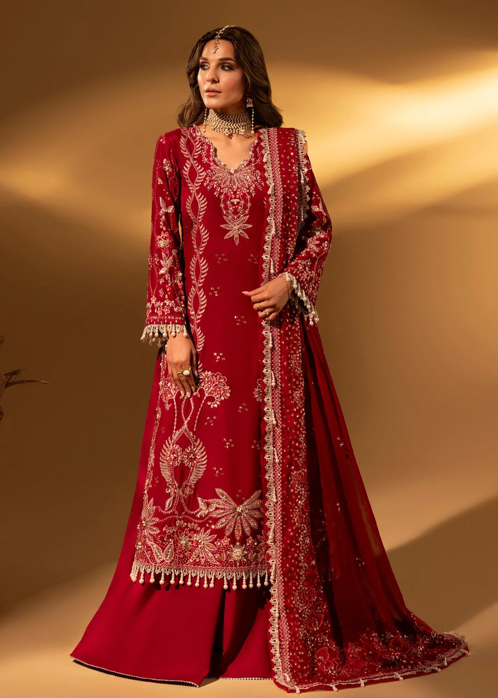 Woman wearing a red embroidered traditional outfit against a warm beige background
