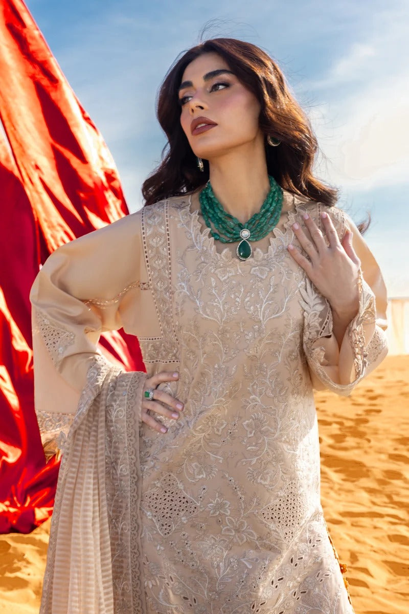Woman in a beige embroidered dress with a green necklace in a desert setting